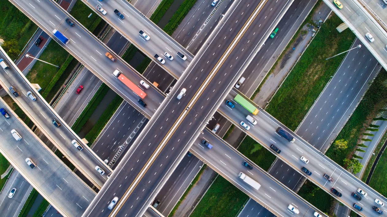 Aerial view of a busy highway interchange with multiple lanes and vehicles in motion.