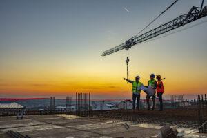 Multi ethnic workers talking at construction site reviewing plans